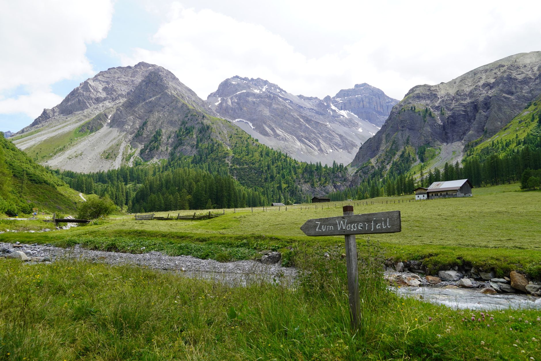 Un panneau indicateur guidant le chemin à travers un paysage alpin suisse luxuriant avec des montagnes majestueuses.
