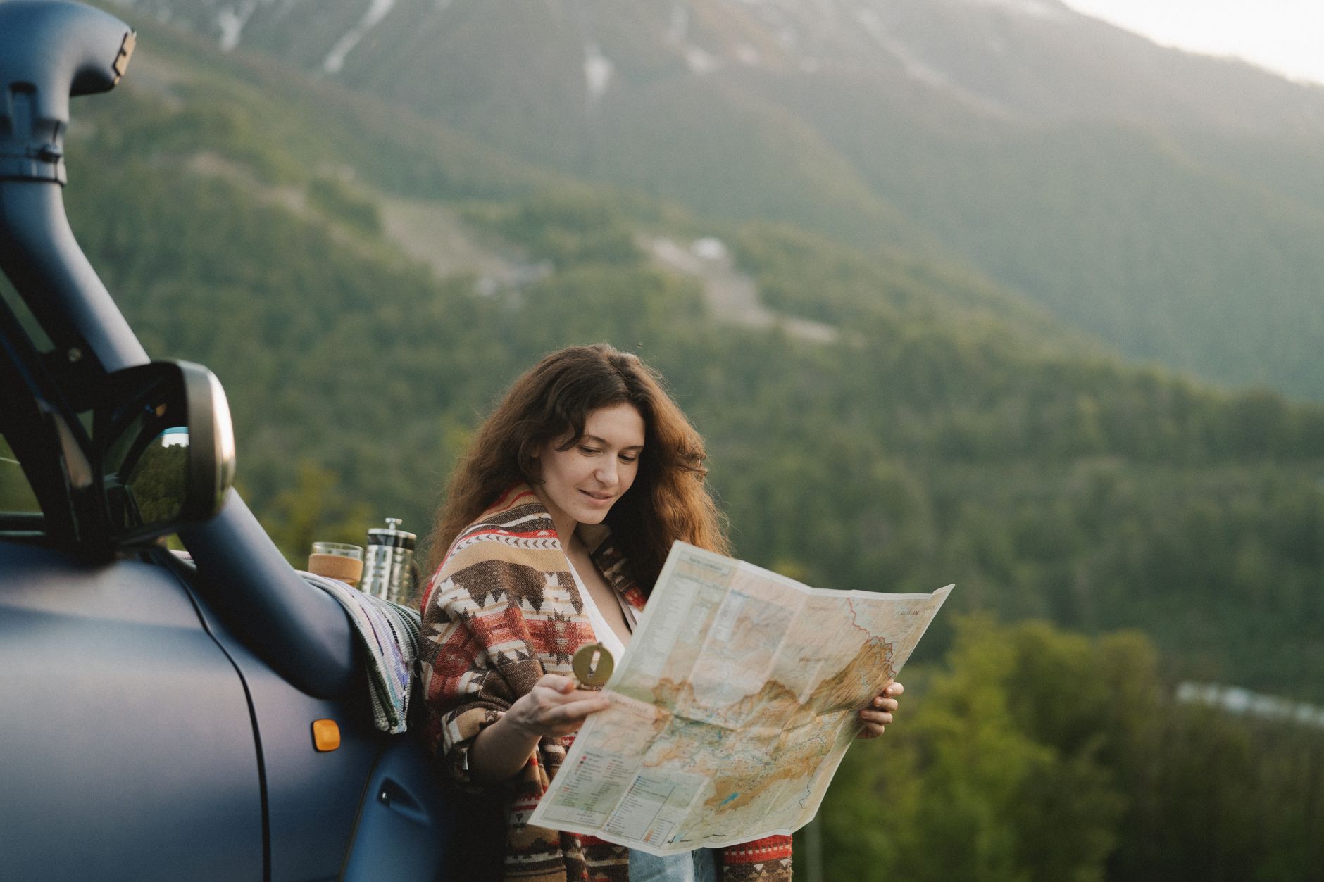 Une femme profite d'un road trip pittoresque en montagne, utilisant une carte pour naviguer sur des paysages magnifiques.